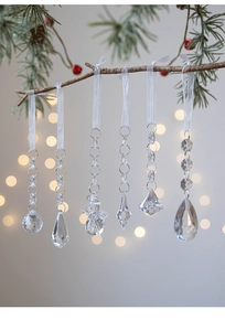 Set of 6 clear acrylic snowflake and drop ornaments hanging on a Christmas tree branch