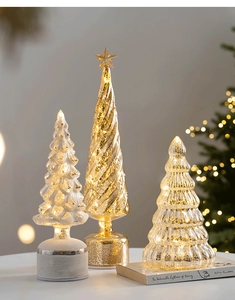 Trois sapins de Noël en verre illuminés avec spirales dorées et flocons de neige