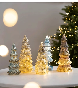 Détail de sapins de Noël en verre lumineux avec éclairage LED sur table en pierre