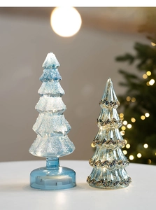 Détail de sapins de Noël en verre LED avec texture de neige et motifs ondulés brillants
