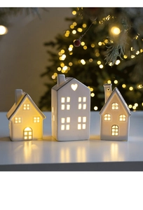Close-up of three white ceramic glowing houses with gold trim and warm LED lights
