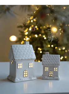 Detail of glowing white ceramic Christmas houses with gold edges and warm LED lights