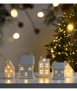 Set of five white ceramic house ornaments with hollow windows and warm glowing light