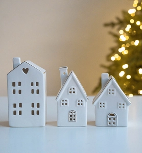 Detail of three white ceramic glowing houses with gold trim and heart shaped cutouts