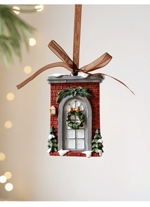 Detail of Christmas resin cottage ornament with snowy trees and a festive green wreath