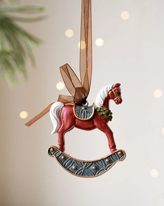 Detailed close-up of a vintage red resin rocking horse ornament with holly decorations