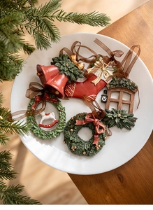 Macro detail of resin Christmas ornaments featuring red bells and stockings on a white tray