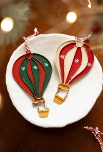 Detail of metal hot air balloon Christmas ornaments with snowflakes on a white plate