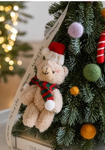 Primer plano de un oso de peluche navideño beige con gorro y bufanda de punto rojo