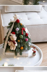 Detalle de mini árbol de Navidad con oso de peluche, adornos coloridos y luces LED cálidas
