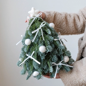 Detalle de mini árbol de Navidad artificial con lazos blancos y estrella de fieltro