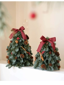 Detalle de árboles de Navidad de mesa con lazos rojos, piñas y palitos de canela
