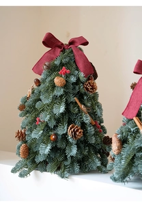 Mini árbol de Navidad con piñas, bayas rojas y un lazo burdeos decorativo