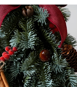 Primer plano de árbol de navidad artificial con bayas rojas, piñas y lazos rojo oscuro