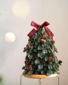 Primer plano de un árbol de Navidad de mesa con lazo rojo, piñas y canela
