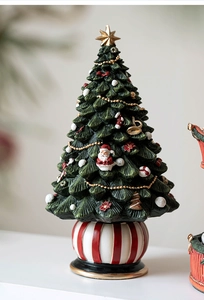 Detail of Christmas tree ornament with golden star, santa figures and red striped base