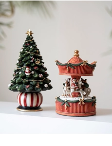 Detail of Christmas tree figurine and red carousel music box with Santa Claus imagery