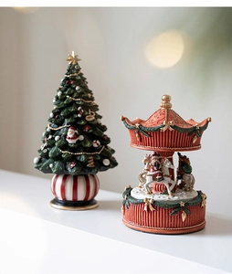 Detail of resin Christmas tree and Santa carousel music box with festive red ornaments