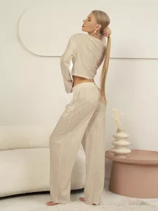 Detail van gebroken witte opengewerkte gebreide set met top met lange mouwen en wijde broek