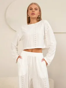 Detail van witte tweedelige eyelet-borduurset met korte top met lange mouwen en wijde broek