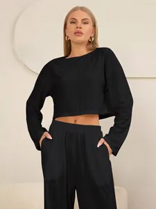 Detail van zwarte tweedelige set met hol borduurwerk op crop top en broek met hoge taille