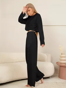 Detail van zwarte gebreide tweedelige set met crop top met lange mouwen en wijde broek