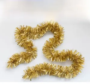 Detail of dense thick gold Christmas tinsel garland with shiny metallic foil texture