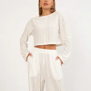 Witte tweedelige damesset met opengewerkte crop top met lange mouwen en bijpassende broek