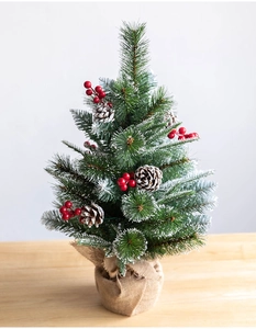 Detail of tabletop Christmas tree with red berries, pine cones and snow-flocked PE branches