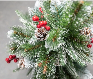 Close-up of frosted Christmas pine branches with red berries and natural pinecones