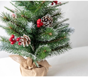 Detail of mini snowy Christmas tree with pine cones, red berries and burlap base