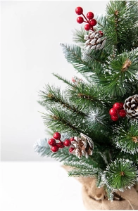 Macro detail of artificial Christmas tree with snow flocking, pine cones and red berries