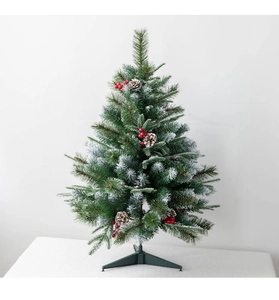 Detailed view of flocked needles, red berries, and pine cones on a desktop Xmas tree