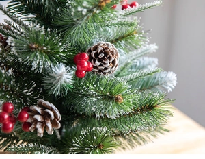 Close-up of decorative Christmas tree branches with red berries and snowy pine cones