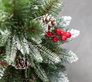 Close-up of frosted pine needles with red berries and pine cones on a Christmas tree