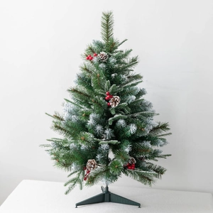 Tabletop snowy Christmas tree with red berries, pine cones and a green stand