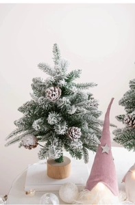 Macro detail of snow-flocked Christmas tree branches with real pinecones and wood base