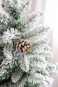 Macro detail of flocked pine needles and natural pine cone on a snow-covered Christmas tree