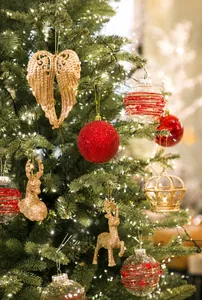 Close-up of golden wings, reindeer, and red glitter baubles on a decorated Xmas tree