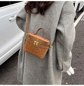 Detail einer braunen Eimer-Handtasche mit Leopardenprägung und goldenem Reißverschluss