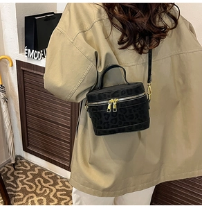 Modèle portant un sac seau noir imprimé léopard avec bandoulière et détails dorés