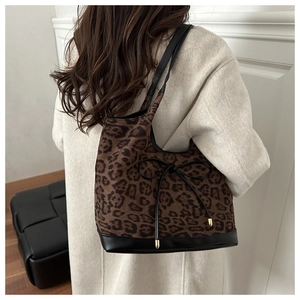 Chic leopard print oversized tote bag with black leather straps shown on shoulder