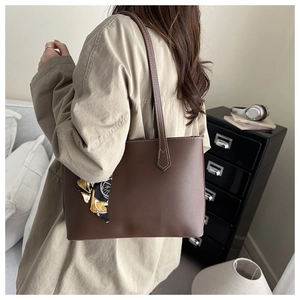 Close-up of a dark brown leather tote bag with a decorative vintage pattern silk scarf