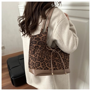 Macro detail of leopard print tote bag with brown leather trim and side bow accent