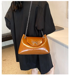 Detail view of caramel brown glossy tote bag with silver bow and metal chain strap