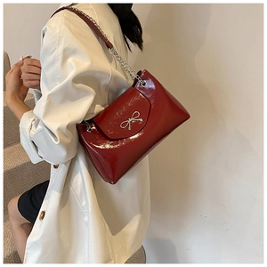 Détail du sac cabas en cuir verni rouge foncé avec boucle nœud argentée et chaîne