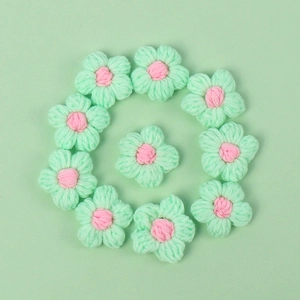 Macro detail of 10 handmade crochet macaron flowers in mint green and soft pink yarn