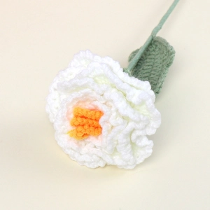 Detailed macro shot of a white and orange handmade crochet peony flower and leaf