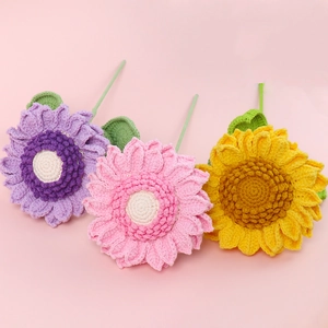 Handmade crochet sunflower bouquet in pastel colors with knitted stems on pink background