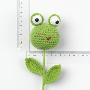 Handmade crochet frog head with dimensions measured by ruler on white background